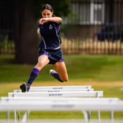 Sydenham High School pupil jumping hurdle at sports ground